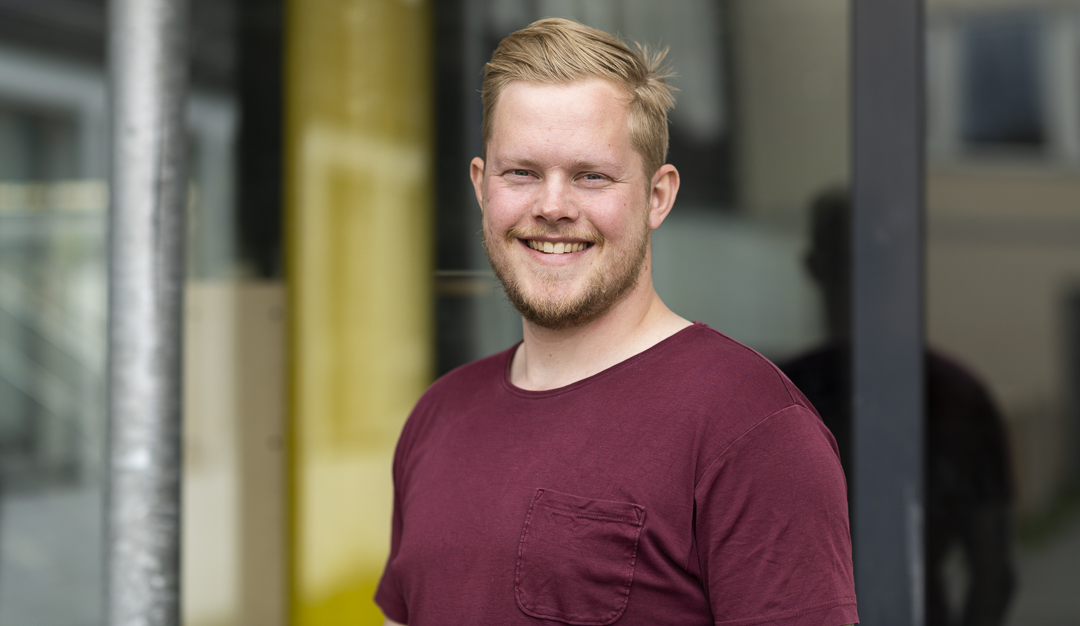 Portrett av kontaktl&aelig;rer Sondre Brekke Valmork foran glassvegg