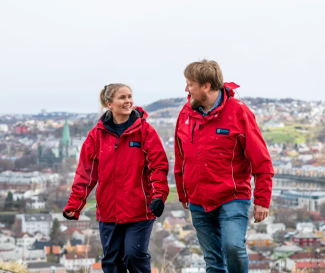 to ansatte som ser på hverandre med like røde jakker