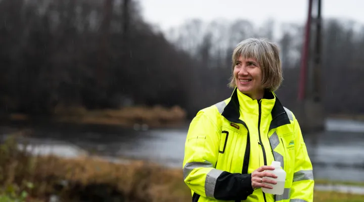 Cecilie portrettert ved en elv og en bro, med en vannprøve i hånda