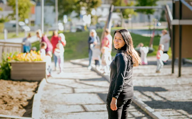 Portrett av Kine med lekende barn i bakgrunnen.