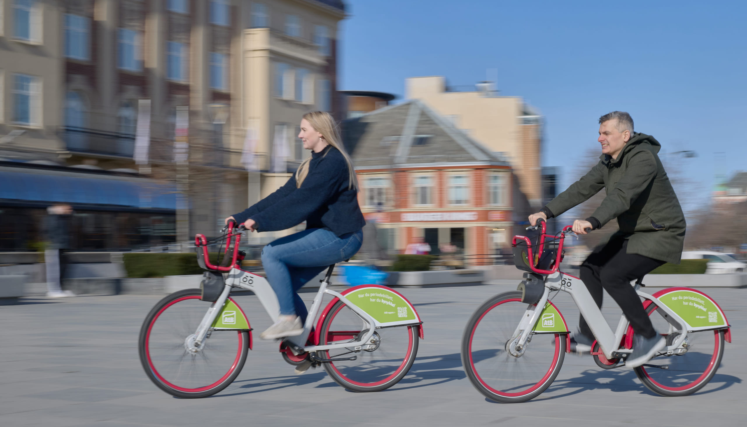 To personer på bysykkel over torvet