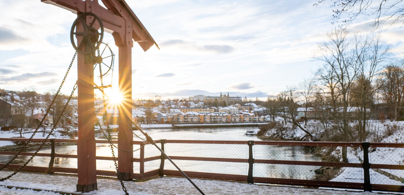 Lav sol over Nidelva med porten på gamle Bybro i forgrunnen