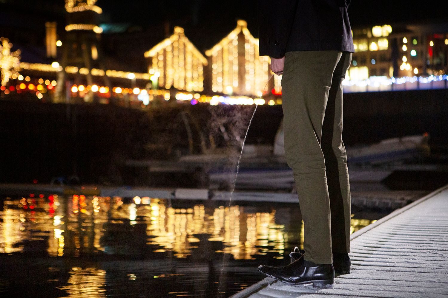 Mann urinerer ved en bryggekant