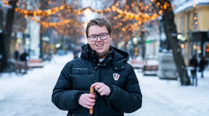 Smilende mann med blindestokk i snødekt gate