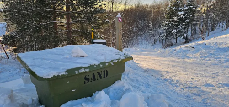 kasse med strøsand og skilt som viser en snarvei