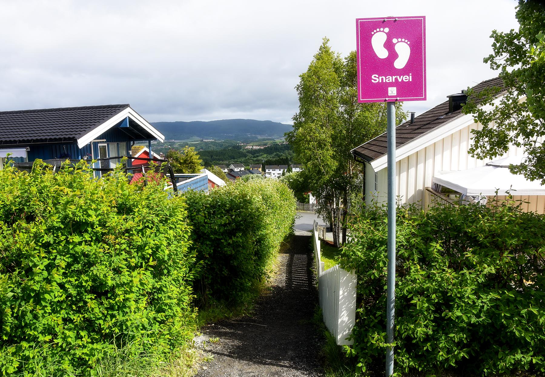 Et skilt med teksten Snarvei langs en grussti