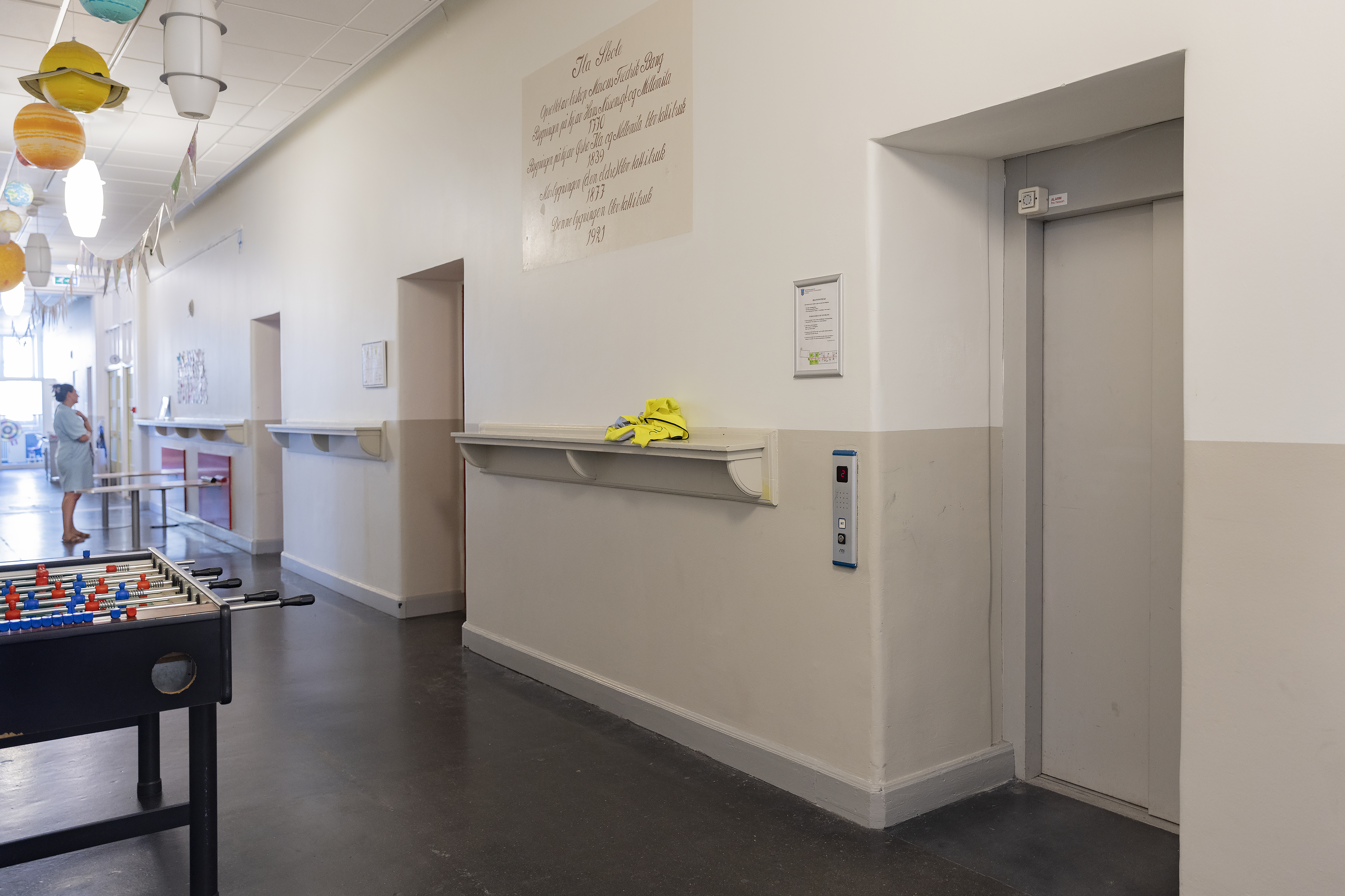 En lang korridor med d&oslash;rer inn til heis og flere klasserom