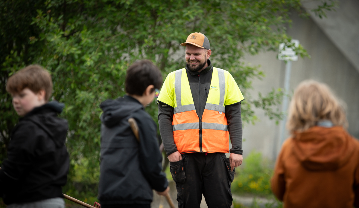 Fire personer på dugnad, en i gul vest.
