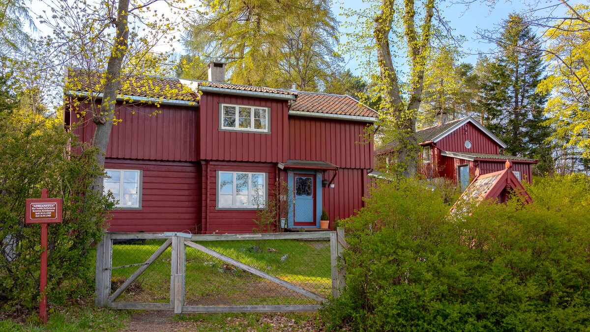 Et rødt trehus med hage