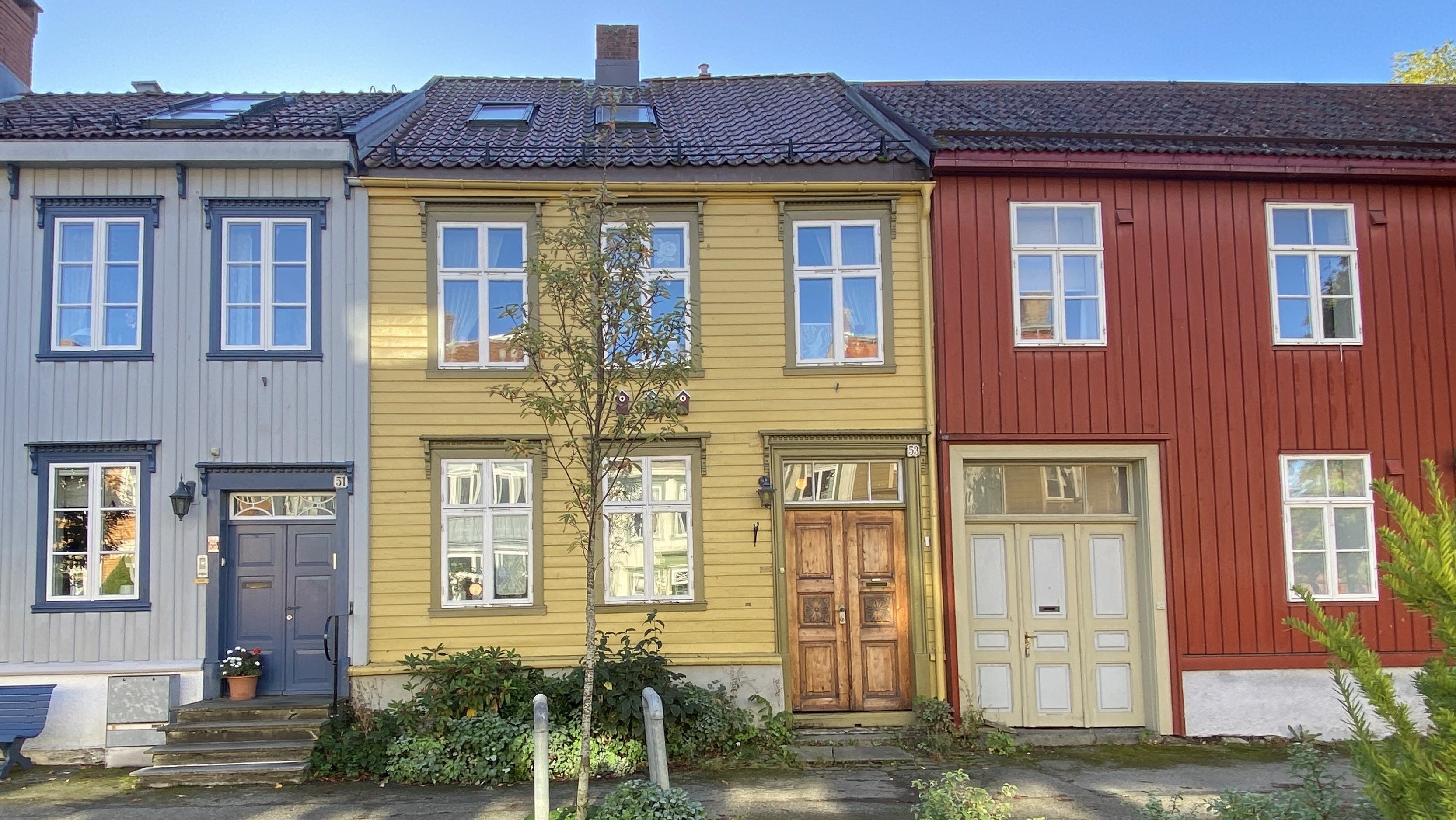 tre hus i rekke i blått gult og rødt