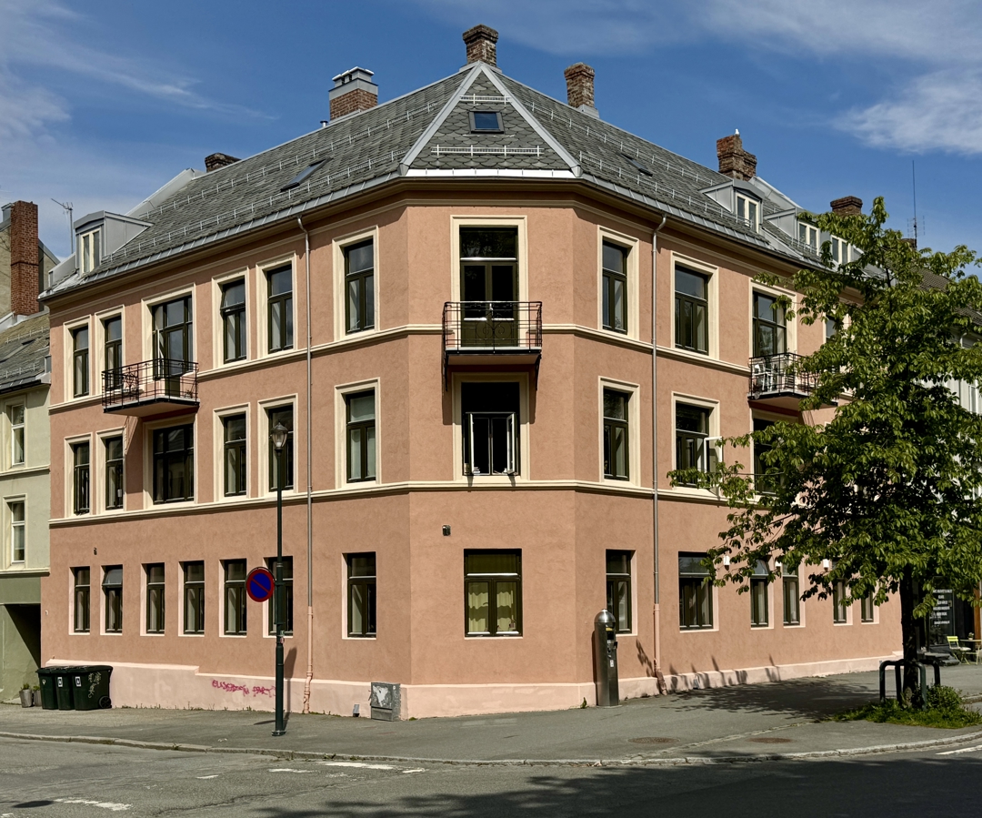 en murbygning i 3 etasjer med rosa farge p&aring; vegg og brune vinduer