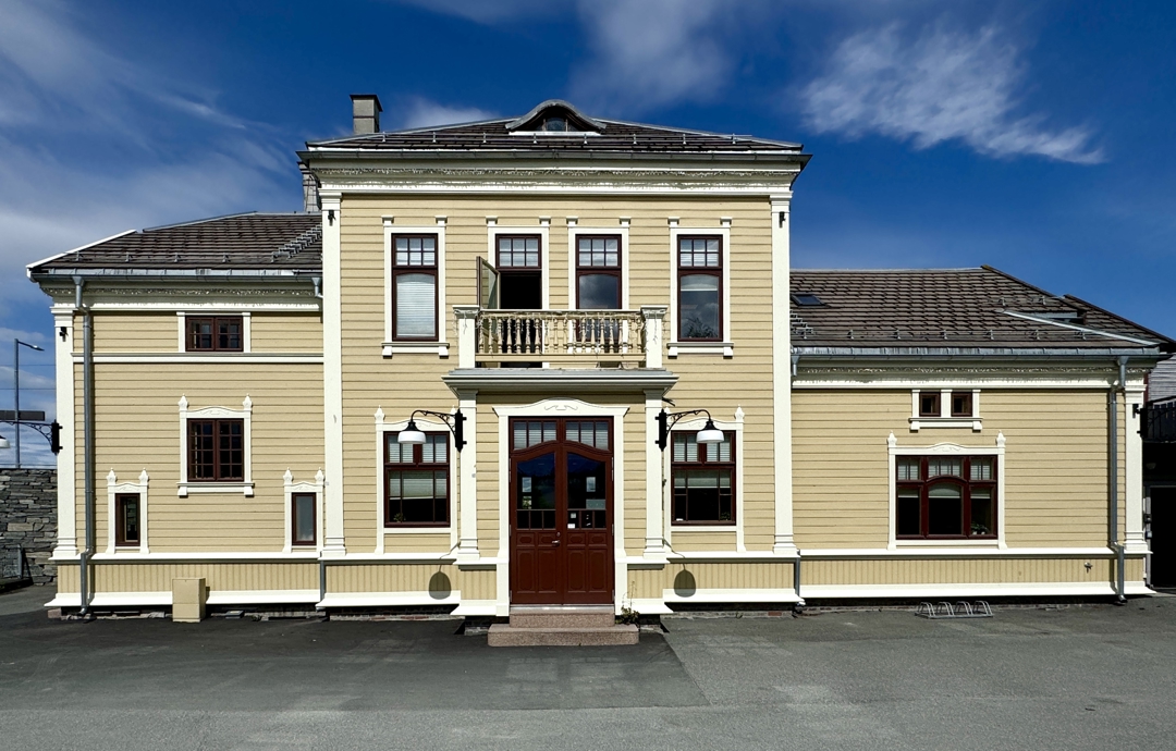 stasjonsbygning i 2 etasjer i lysgul veggfarge og dyp r&oslash;dbrune vinduer