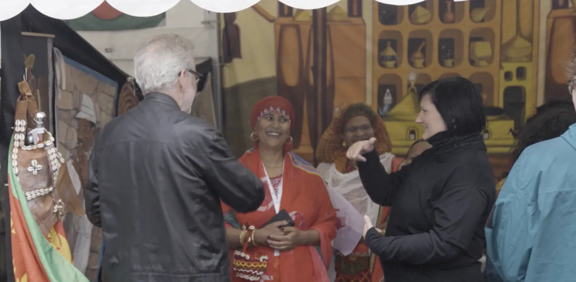 En kvinne og en mann står i et telt med kvinner kledd i tradisjonelle kostymer fra Nord-Afrika.