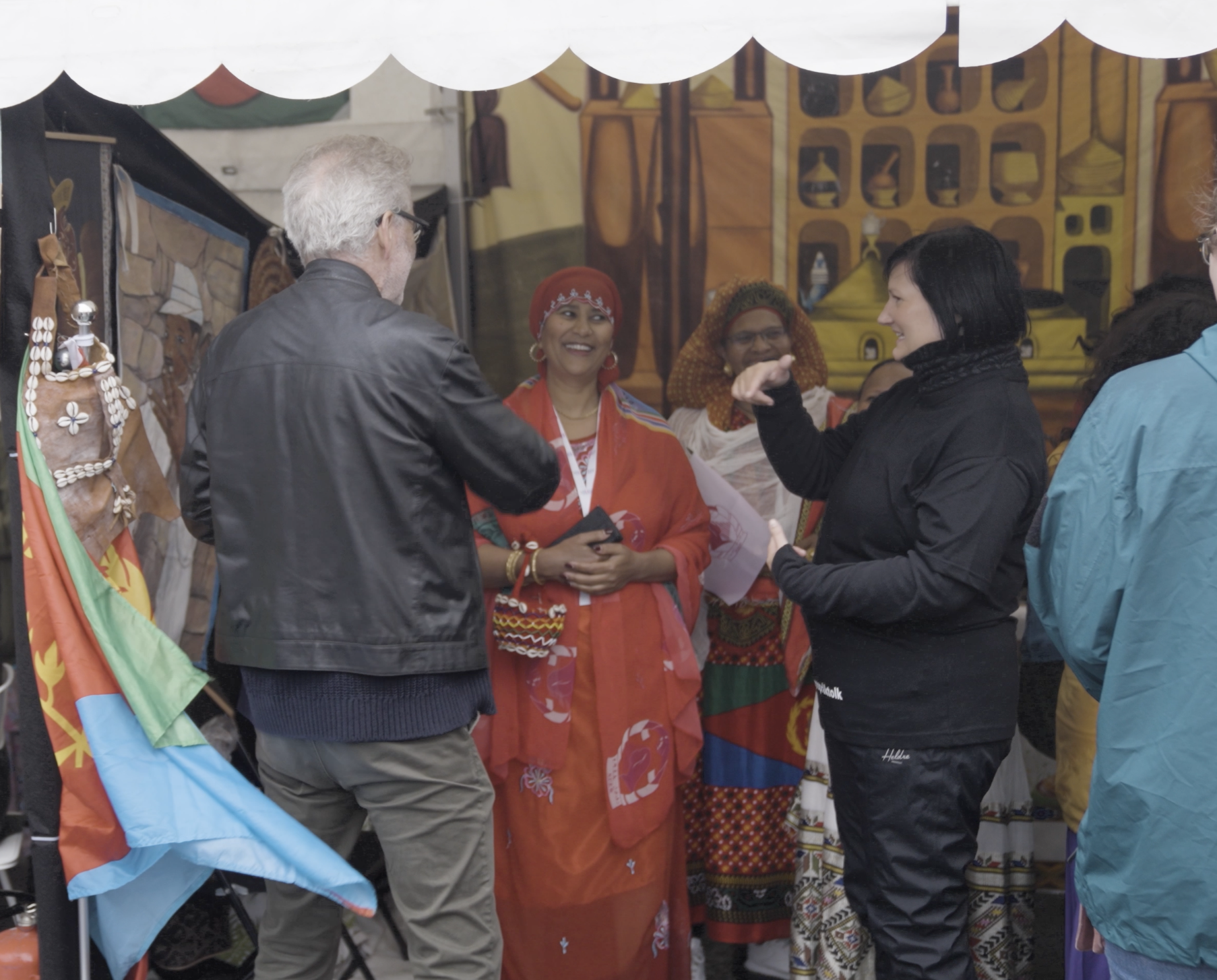 En kvinner tegnsp&aring;rktolker for en mann ved en markedsbod.