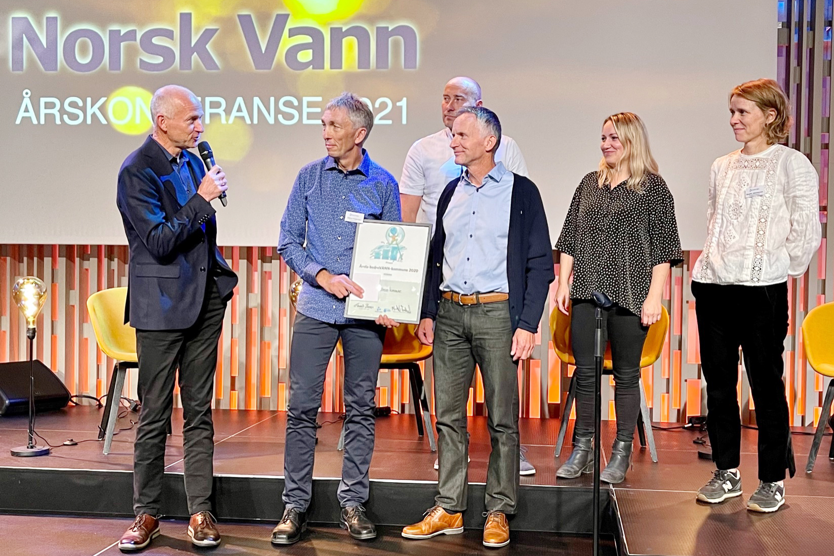 Prisutdeling med seks mennesker på en scene