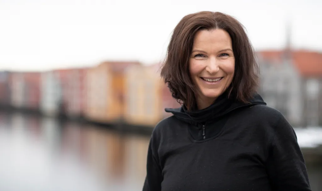 Portrett av parkeringsbetjent Marie på Gamle Bybro med Nidelva og bryggerekken i bakgrunnen.