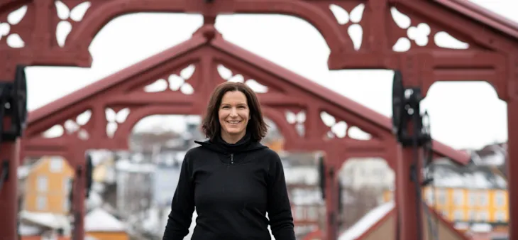 Foto av trafikkbetjent Marie i sivile klær under Lykkens portal på Gamle Bybro. I bakgrunnen skimtes Brobakken og deler av Bakklandet.