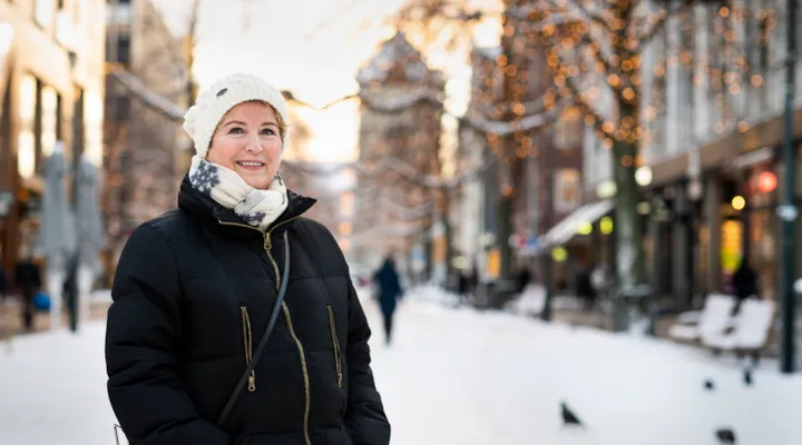 Portrett av Kirsti Vandbakk i Nordre om vinteren, med vinterbelysning og snø på gata i bakgrunnen.