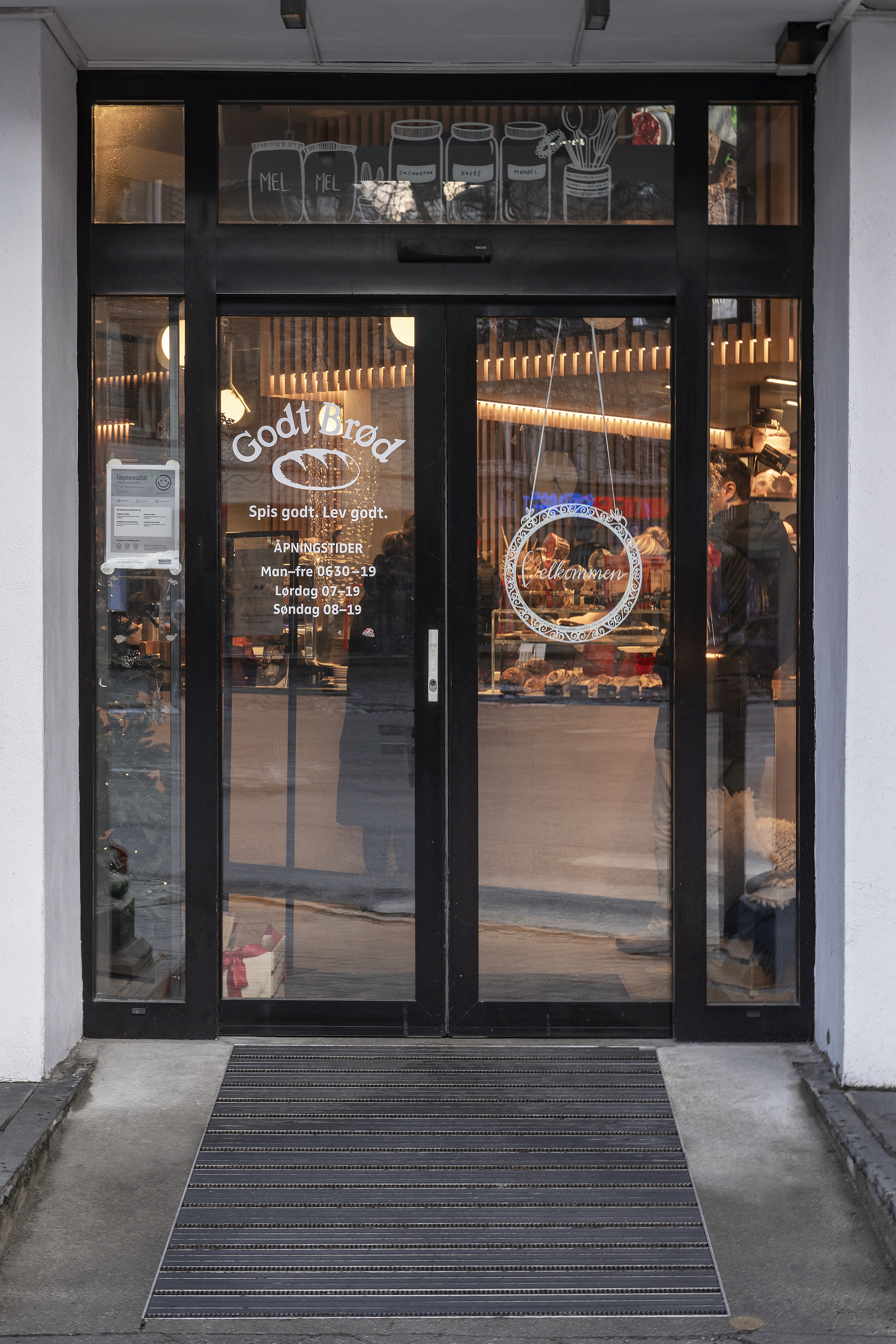 N&aelig;rbilde av d&oslash;rer med p&aring;klistrede logoer og &aring;pningstider.