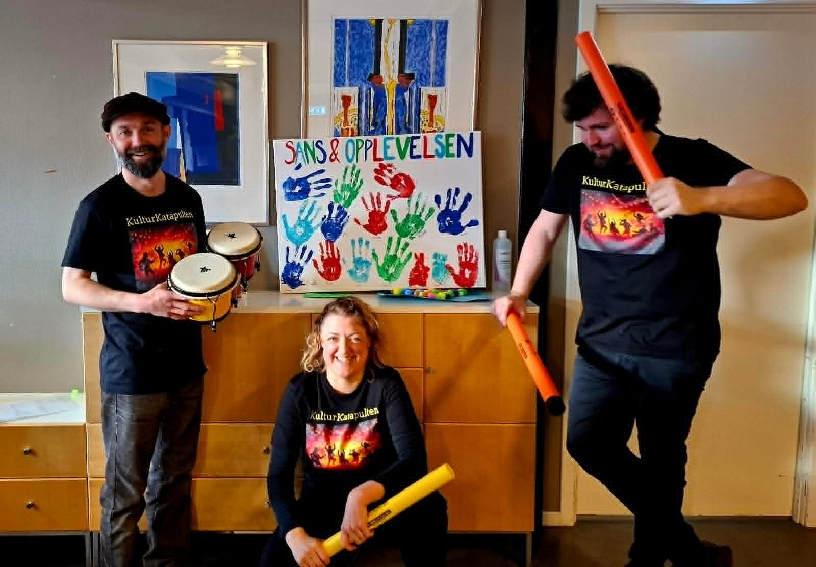 Tre personer fra Kulturkatapulten som viser fram instrumenter
