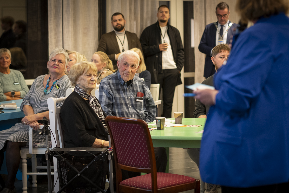 En eldre mann og en eldre kvinne sitter i publikum og smiler.
