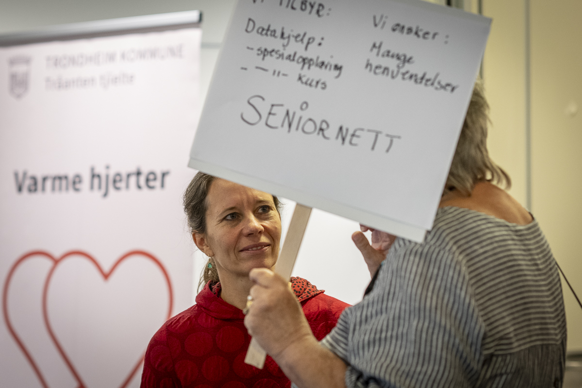 En kvinne står foran et skilt der det står "varme hjerter".