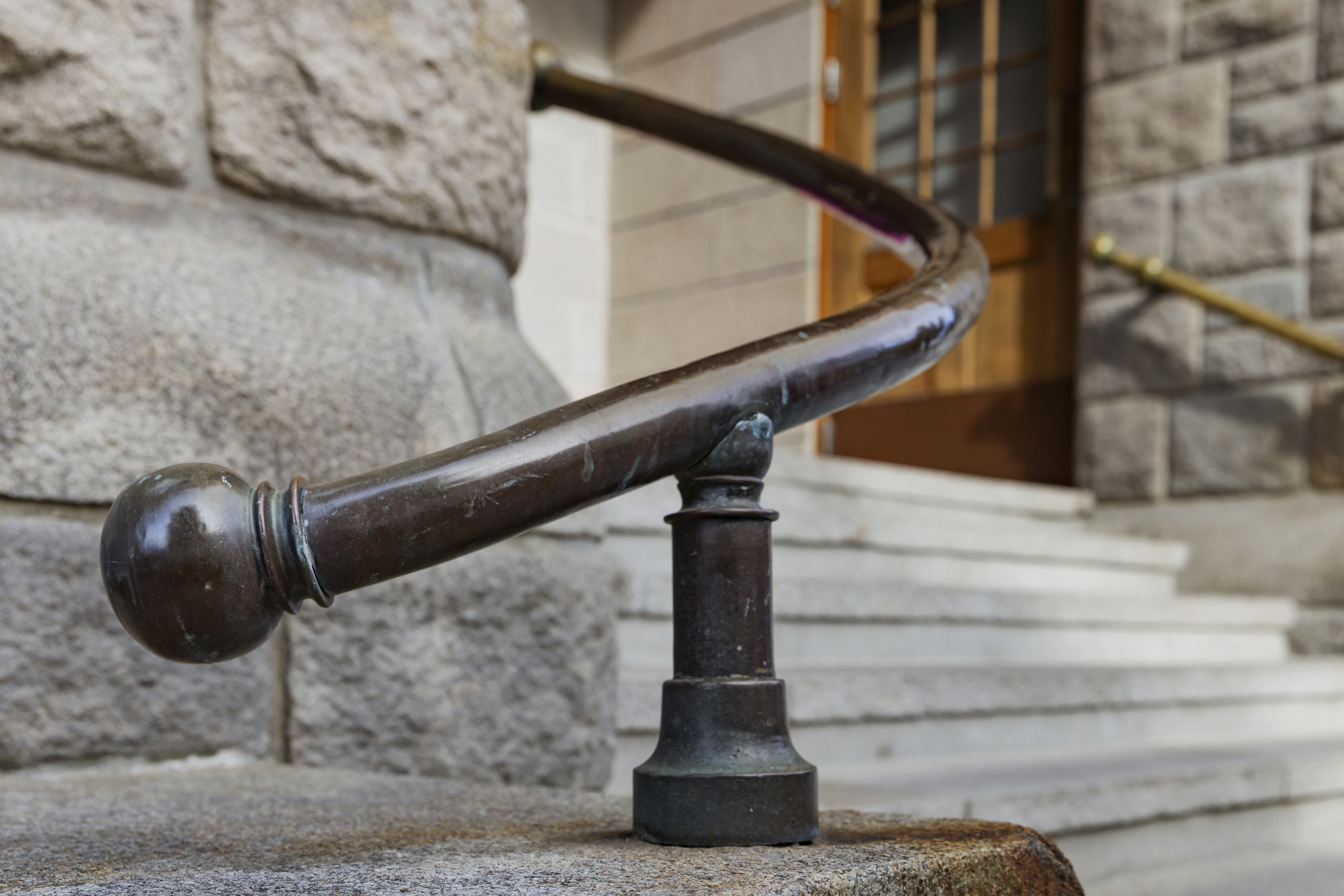 H&aring;ndl&oslash;per i brunt kobber p&aring; side av hovedinngang til Posten Moderne