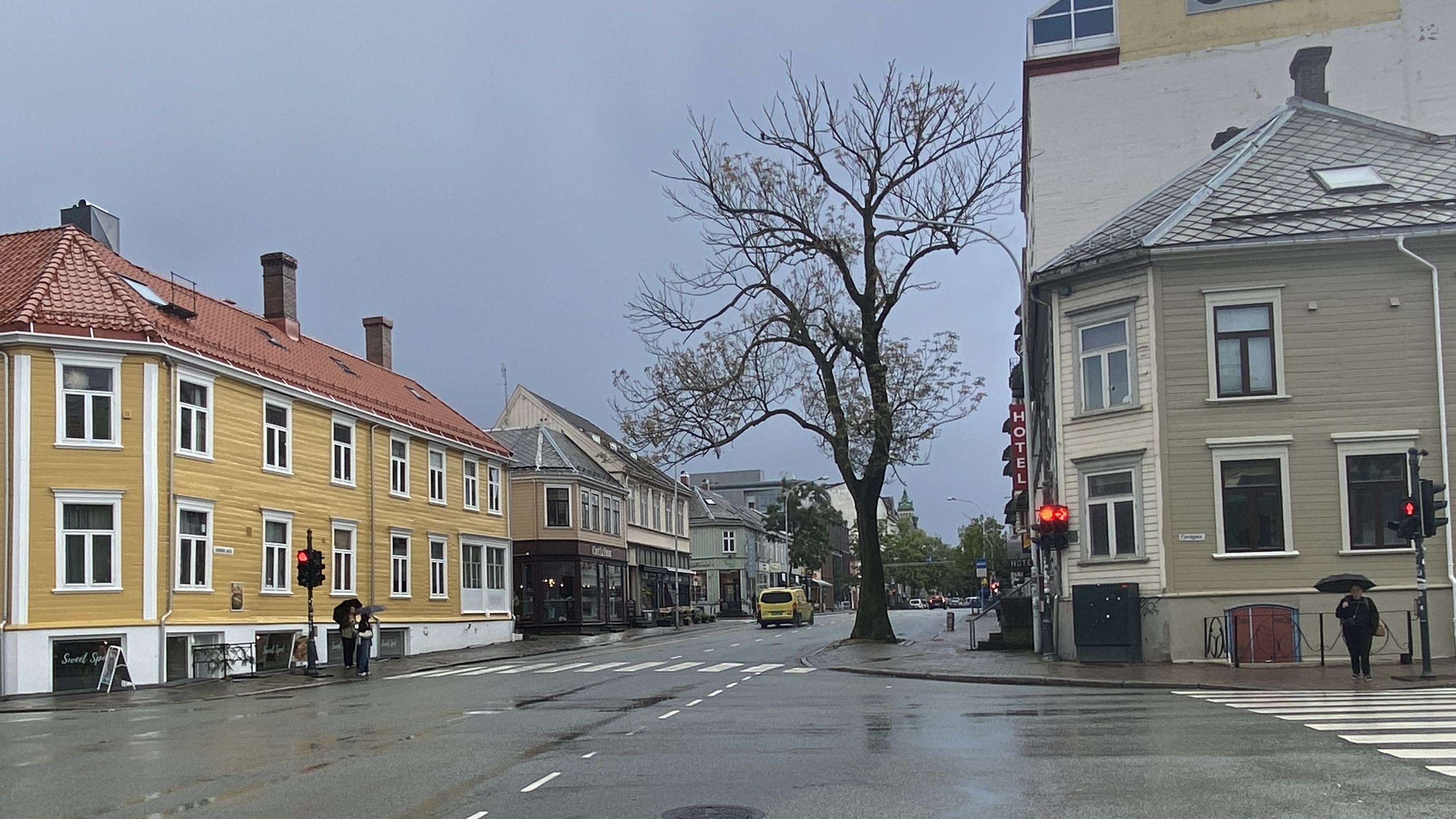 Et gatekryss med trebygg i rekke p&aring; hver side av veien