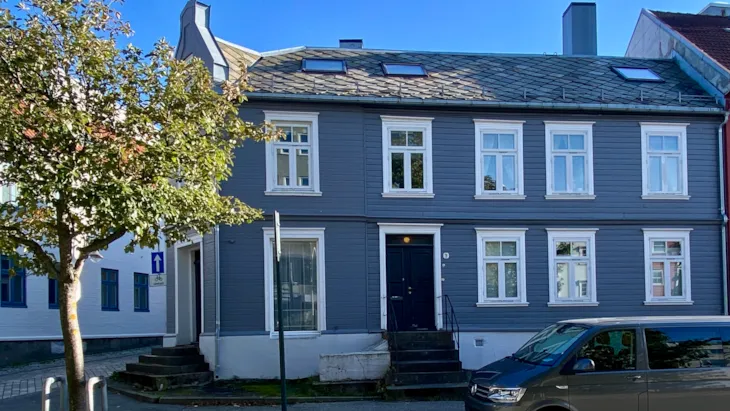 Grå bygning i to etasjer der del av bygningen er oppført i mur
