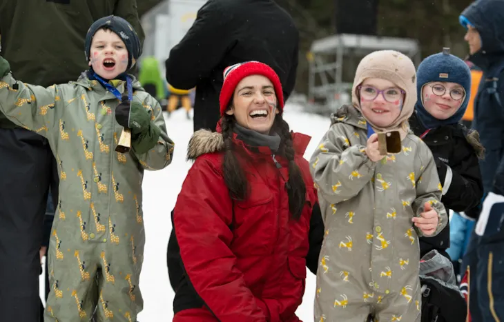 En kvinne og tre barn smiler mot kamera.