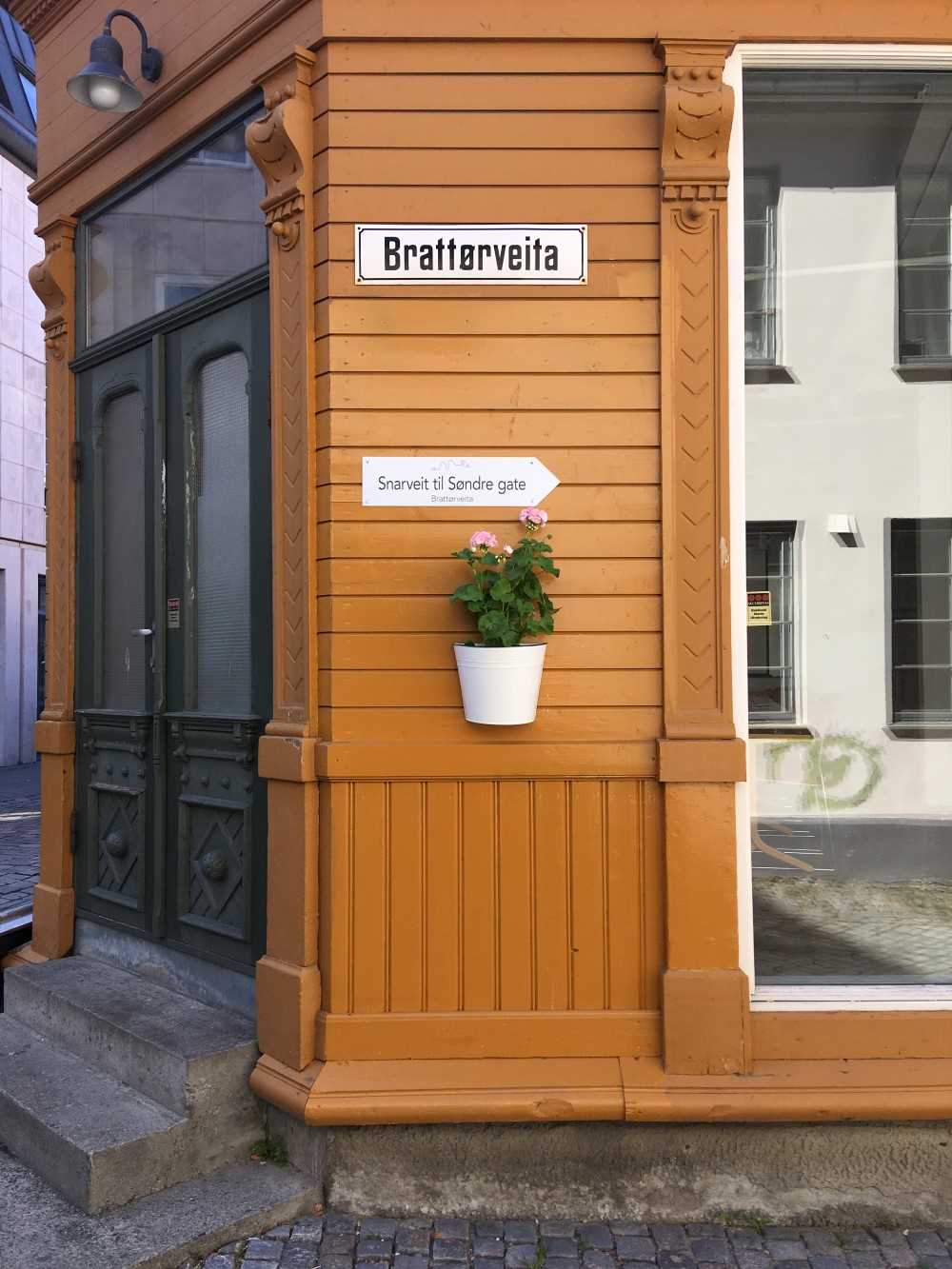 Hushj&oslash;rne med snarveit-skilt og plante p&aring; vegg