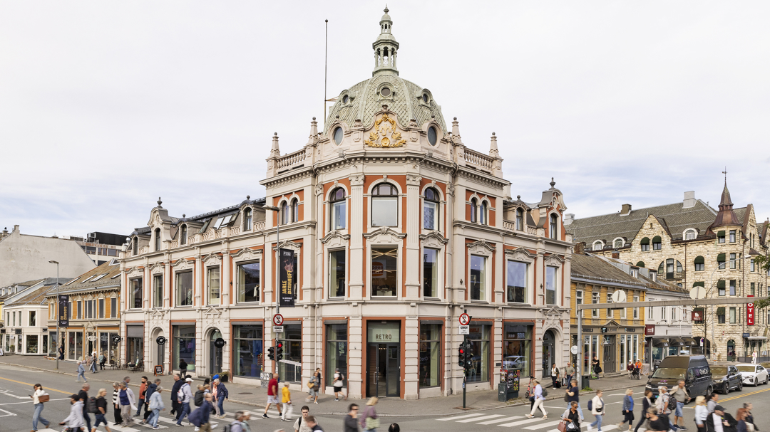 Bilde av bygningen fra avstand slik at man ser inngang på hjørne og begge hovedfasader