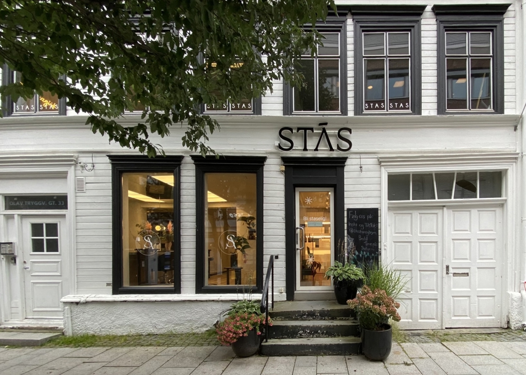 Foto av liten trebygning med næring i første etasje. Det er en høy trapp opp til første etasje.