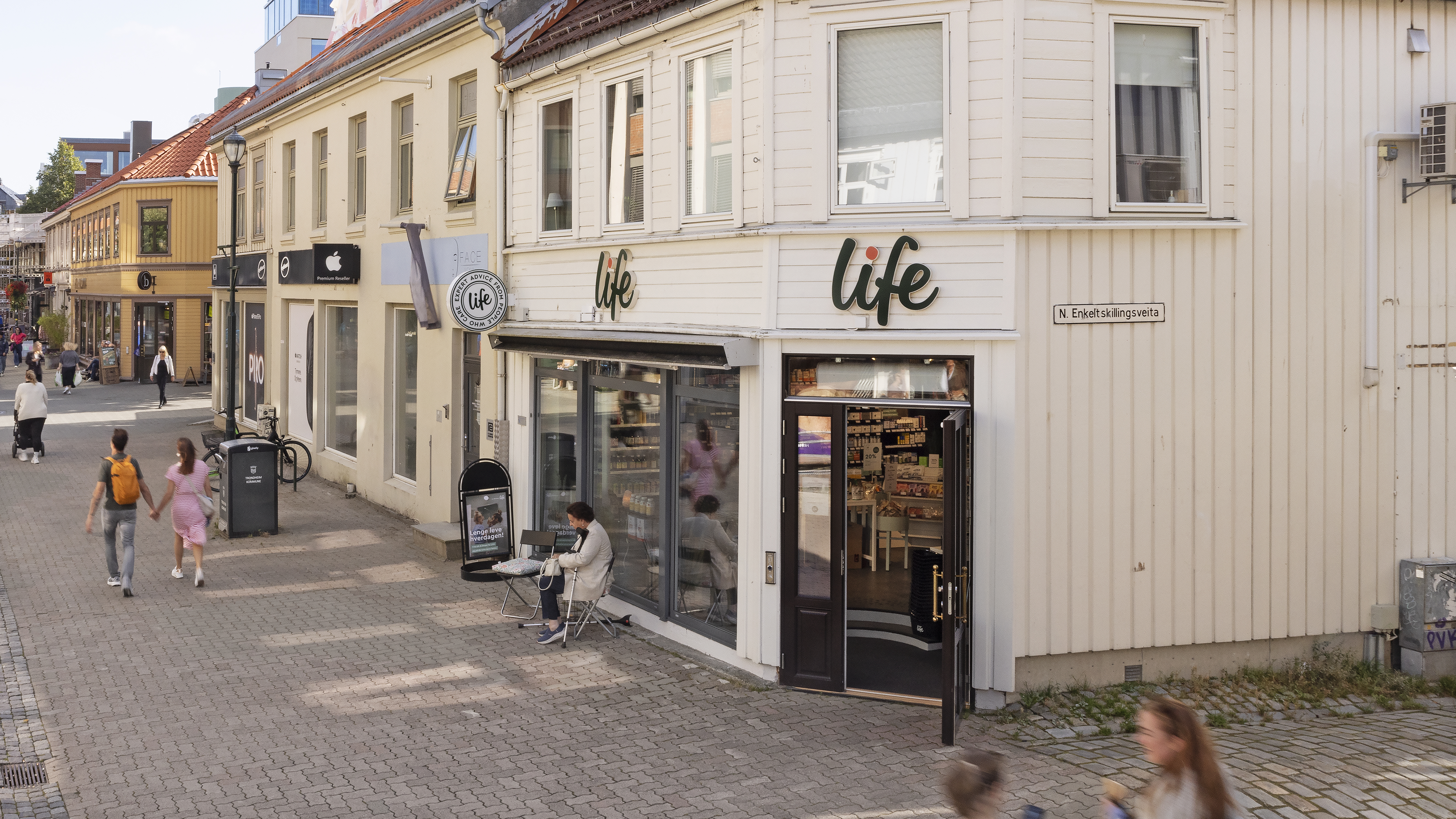 Viser en tregård i to etasjer med inngang til forretning på hjørnet