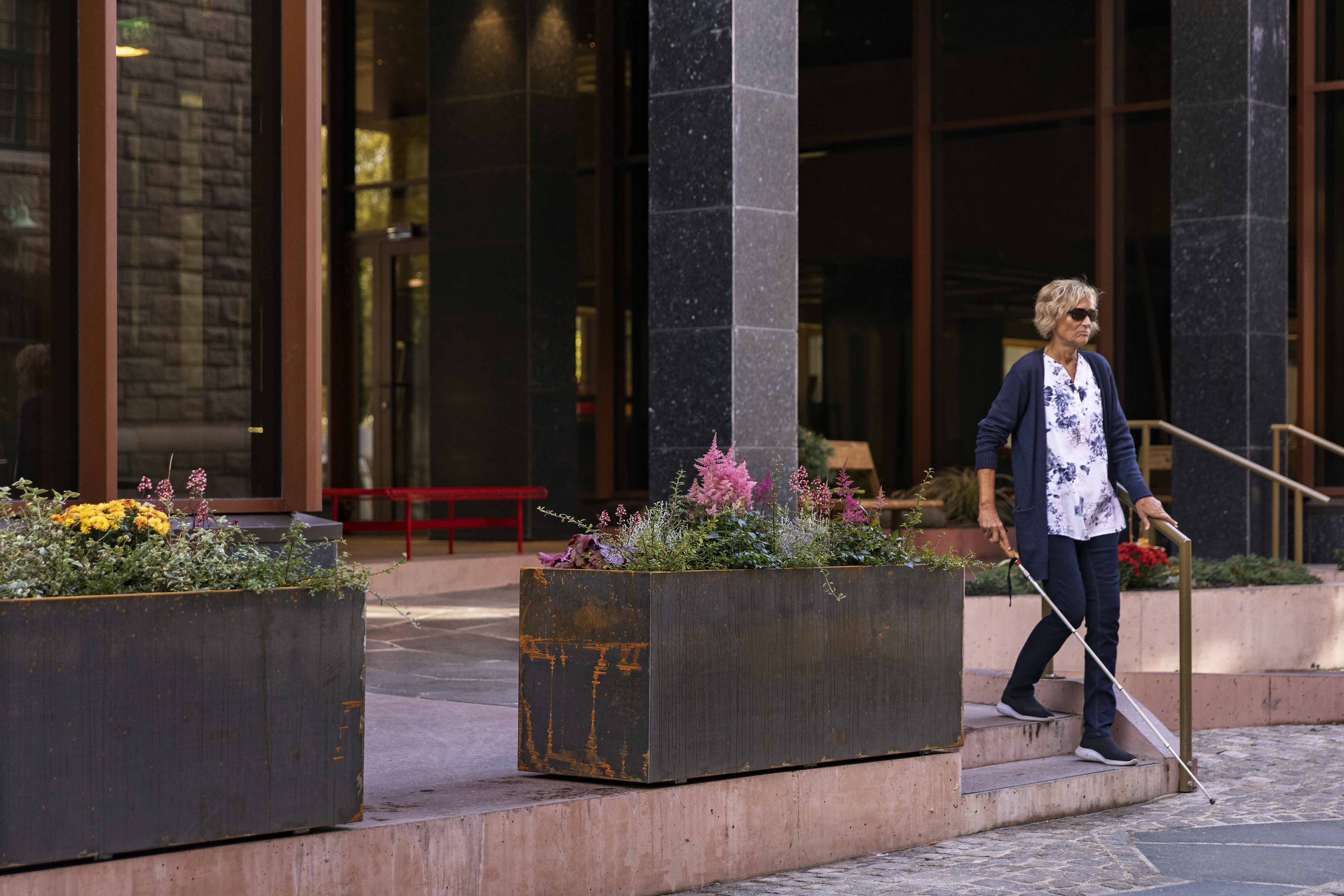 Person med mobilitetsstokk går ned en trapp.