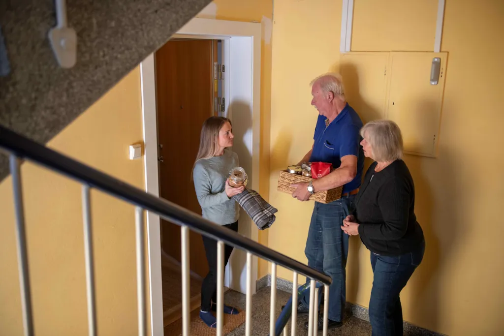 Beredskapsvenner som hjelper hverandre i en krise. Et voksent par hjelper en ung kvinne med varer.