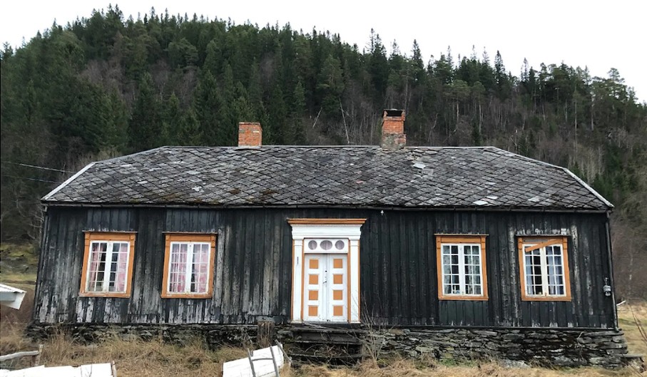 Hus med mørkt panel, skifertak og natursteinsmur