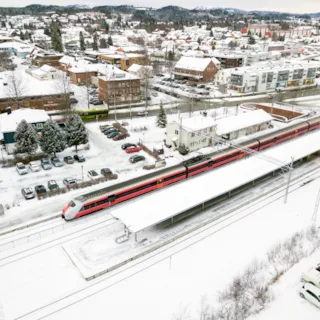 Dronebilde av Heimdal stasjon med togstasjon i fremgrunnen og Heimdal sentrum i bakgrunnen