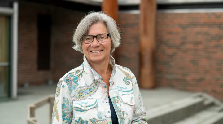 Portrett av rektor Gro Kristiansen foran inngangspartiet til Dalgård skole og ressurssenter.