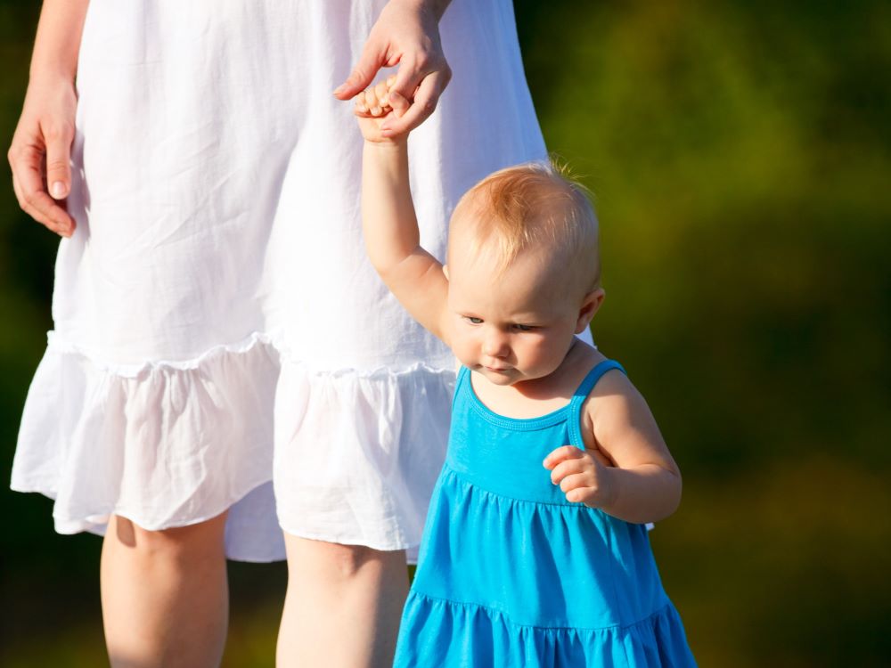 En mors som holder sitt barn i hånden