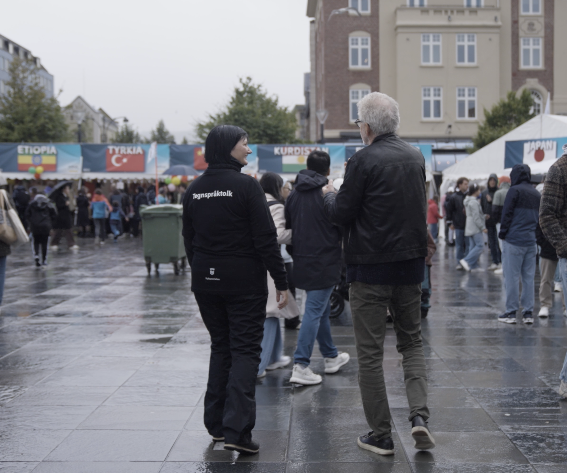 Bilde av mann og kvinne bakfra på et festivalområde.