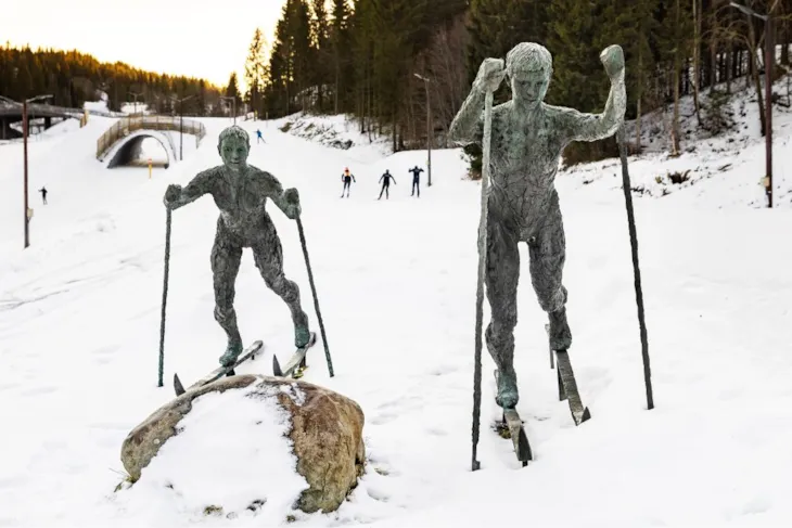 To statuer av barn som går på ski, med skiløyper i bakgrunnen