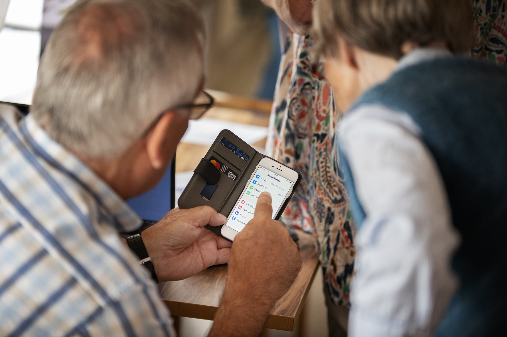 Eldre mann veileder eldre dame i bruk av smarttelefon