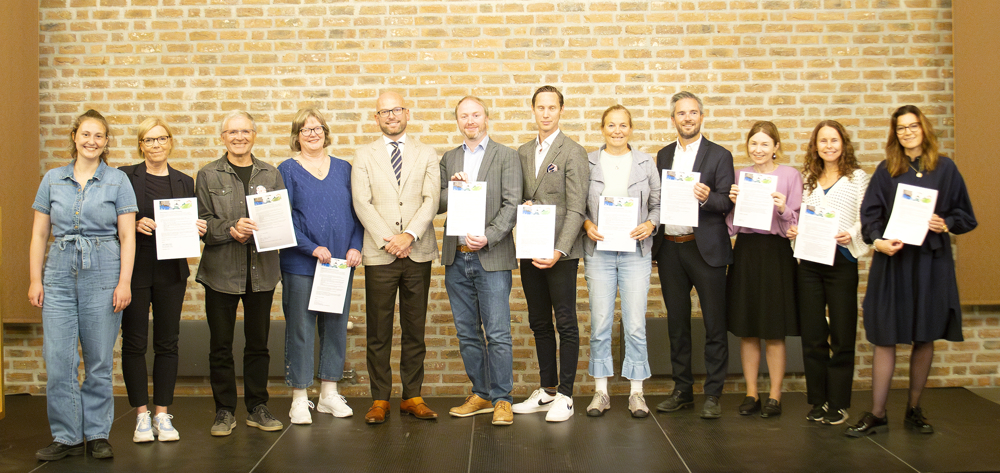 Deltakere p&aring; frokostm&oslash;tet holder opp kopier av den signerte avtalen.