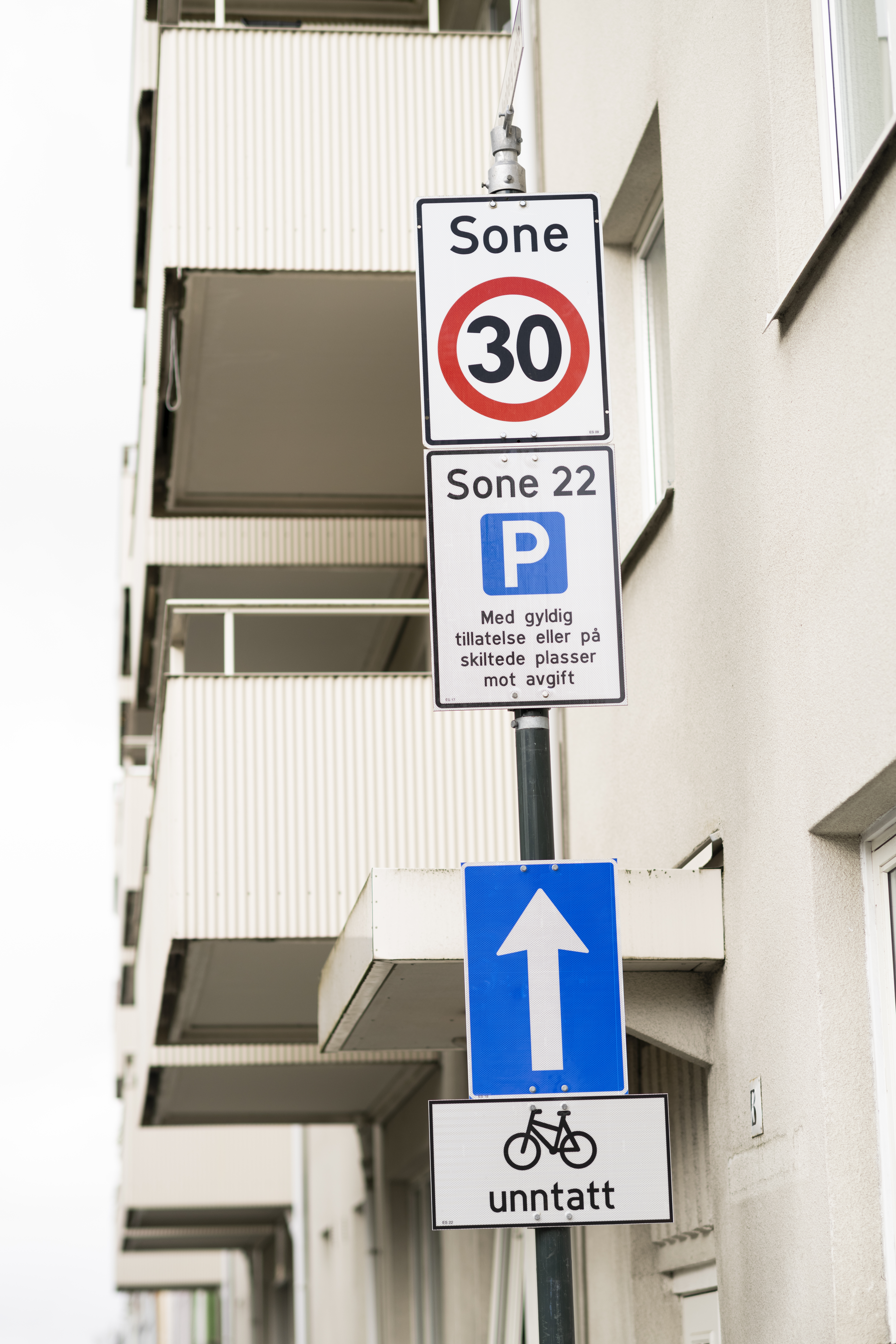 Skiltstolpe foran hvit boligblokk.