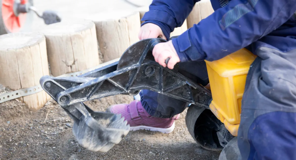Barn med lekegravemaskin i sandkassa