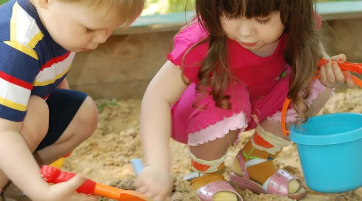 en gutt og en jente som bruker spade i sandkassa