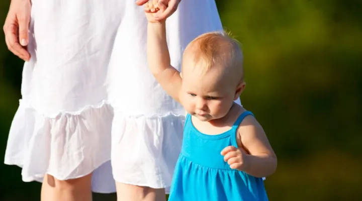 En mors som holder sitt barn i hånden