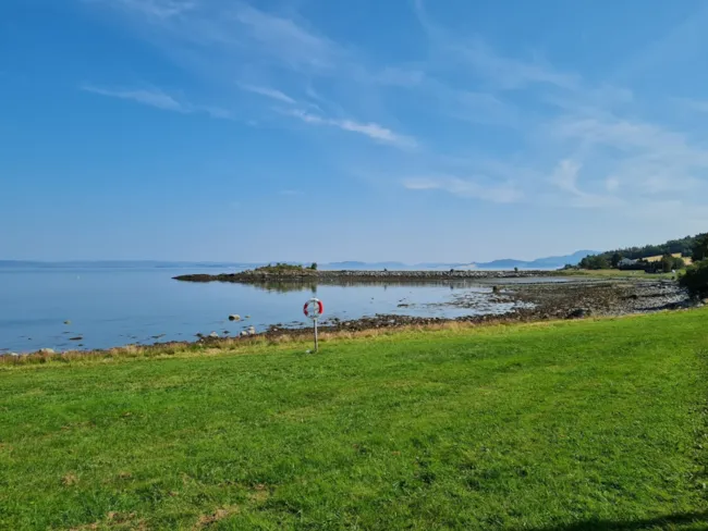 Gressplen med redningsbøye foran fjorden