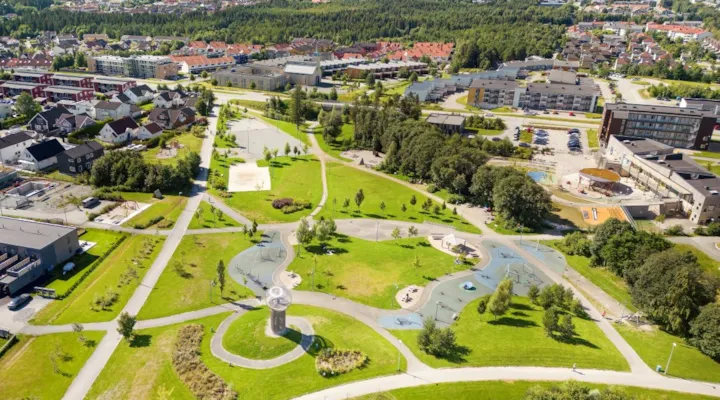 Dronebilde over stor park med lekeområder og grønne plener.
